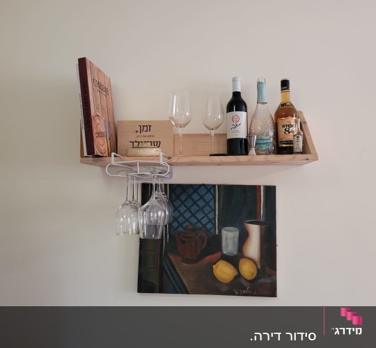 מדף עץ עם בקבוקי יין וכוסות תלויים